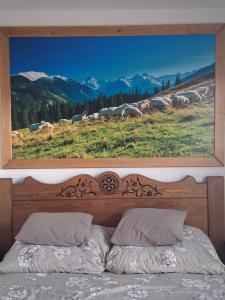 a bedroom with a painting above a bed at Apartament pod Lipa blisko Term Chochołowskich in Ratułów