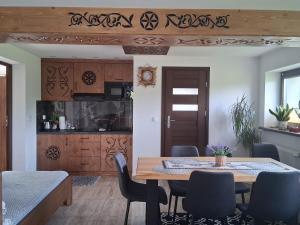 a dining room with a wooden table and chairs at Apartament pod Lipa blisko Term Chochołowskich in Ratułów