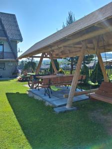 a pavilion with picnic tables and benches in a yard at Apartament pod Lipa blisko Term Chochołowskich in Ratułów