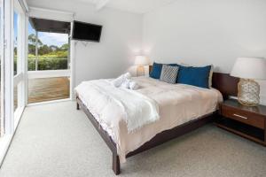 a bedroom with a large bed and a window at The Deck House in Lorne
