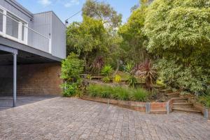a house with a brick driveway next to a building at The Deck House in Lorne