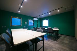 大分市にあるHOTEL 910の緑の壁、テーブルと椅子が備わる会議室