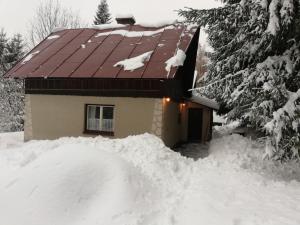 a house with a pile of snow in front of it at Chata v Poustce in Benecko