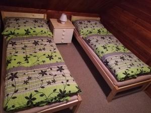 two twin beds in a room with a table at Chata v Poustce in Benecko