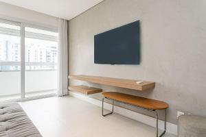 a living room with a desk with a tv on the wall at WI-FI 200MB | Rooftop | Pool with Sea View #CA70D in Florianópolis