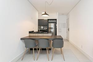 a kitchen with a table and three chairs at WI-FI 200MB | Rooftop | Pool with Sea View #CA70D in Florianópolis