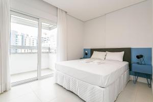 a white bedroom with a large bed and a window at WI-FI 200MB | Rooftop | Pool with Sea View #CA70D in Florianópolis