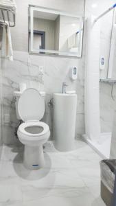 a white bathroom with a toilet and a mirror at Hotel Fuego Bronx near Yankee Stadium in Bronx