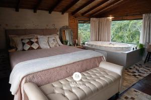 a bedroom with a bed and a tub and a couch at Chalé do Campinho - Rancho Queimado/SC in Rancho Queimado