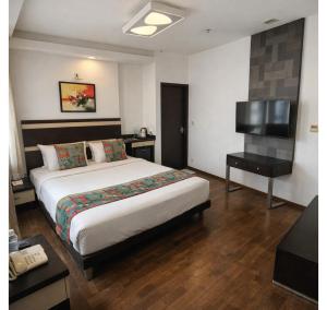 a hotel room with a bed and a flat screen tv at Purple Brigade, Bangalore in Bangalore