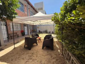 a group of chairs and a table under a white umbrella at Complejo Samaya in San Clemente del Tuyú