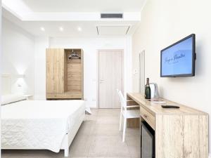 a white bedroom with a bed and a desk with a tv at Borgo dei Pescatori - SUL MARE in Capo Vaticano