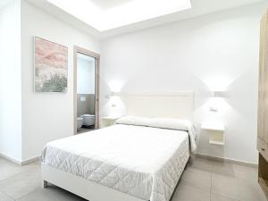 a white bedroom with a bed and a bathroom at Borgo dei Pescatori - SUL MARE in Capo Vaticano