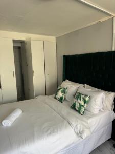 a large white bed with green and white pillows at Legacy lodge in Goodwood