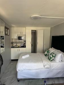a bedroom with a large white bed and a kitchen at Legacy lodge in Goodwood +8 photos