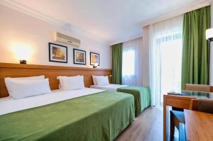 two beds in a hotel room with green curtains at Fethiye Park Hotel in Fethiye +69 photos