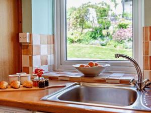a kitchen sink with a bowl of fruit next to a window at 2 Bed in Keswick oc-sz145 in Braithwaite