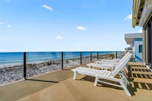 a balcony with white chairs and the beach at Honeysuckle Blue in Pensacola Beach