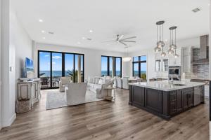 a large kitchen and living room with white walls and wood floors at Honeysuckle Blue in Pensacola Beach