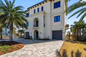 a large white house with palm trees in front of it at Honeysuckle Blue in Pensacola Beach +88 photos
