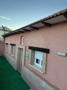 a pink building with two windows and green grass at Casa rural El Terreno in Teruel