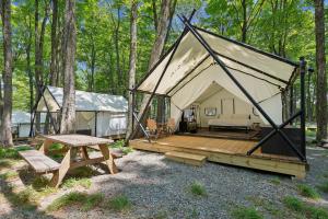 a tent in the woods with a bench and a table at Ferncrest Campground in Greentown