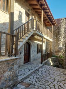a stone house with a wooden staircase and a door at Andromahi Stone House in Stemnitsa