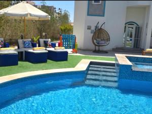 a pool with chairs and a table and an umbrella at Luxury Royal Blue Family Villa 8pers private pool in Hurghada