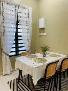a dining room table with chairs and a vase of flowers on it at Homestay Teratak Nailufar in Pekan +5 photos