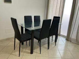 a glass table with four black chairs around it at Larriba Santa Maria by RPG Group in Santa Maria