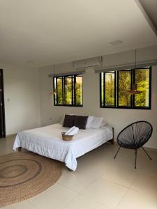 a bedroom with a bed and a chair and windows at Casa Del Río in Montería