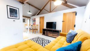 a living room with a yellow couch and a television at The Cartshed in Llanvetherine
