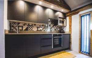 a kitchen with black cabinets and a sink at The Cartshed in Llanvetherine