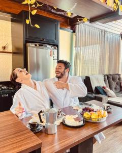 two people sitting at a table in a kitchen at Chalé Mirante dos Anjos in Rodeio