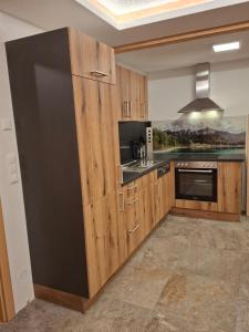 a kitchen with wooden cabinets and a black refrigerator at Mittagsspitz am Bauernhof in Flattach
