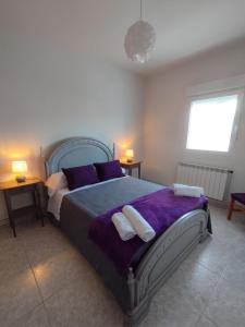 a bedroom with a large bed with purple sheets and pillows at Alojamiento La Tortuga in Las Navas del Marqués