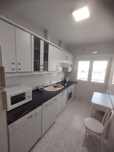 a white kitchen with a sink and a microwave at Alojamiento La Tortuga in Las Navas del Marqués