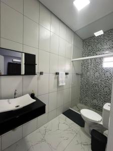 a white bathroom with a sink and a toilet at Apartamento no Centro de Sengés Quarto 01 in Sengés