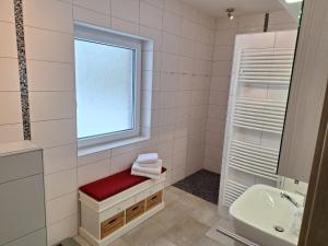 a white bathroom with a window and a red bench at Huus 8 in Westoverledingen +26 photos