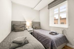 two beds in a small bedroom with a window at Central Platinum Apartments 14 in Rybnik