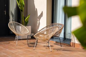 three wicker chairs sitting next to a window at Castell Beach Aparthotel in Castelldefels