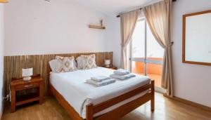 a bedroom with a bed with white sheets and a window at El Shaddai 3 in Atalaia