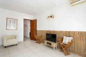 a living room with a television and a chair at El Shaddai 3 in Atalaia