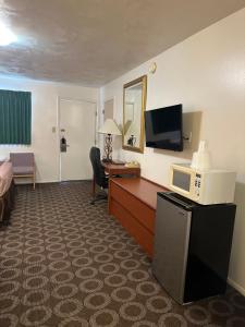 a hotel room with a bed and a desk with a microwave at Canyonlands Motor Inn in Monticello