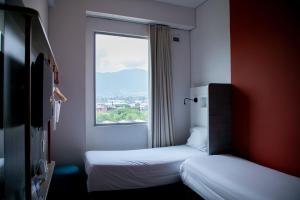 two beds in a small room with a window at ibis budget Medellín Itagüí Metro in Medellín +51 photos