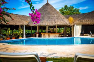 a resort with a swimming pool with a thatch roof at Keur Saloum Resort in Toubakouta