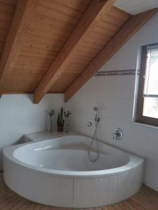 a large white tub in a room with a wooden ceiling at Ferienwohnung Bermbach in Weilburg +37 photos
