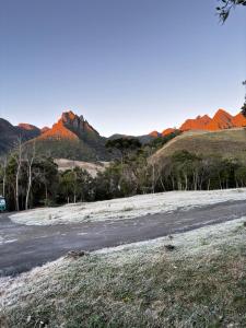 a dirt road with red mountains in the background at Cabana do Céu - Soldados Sebold in Alfredo Wagner