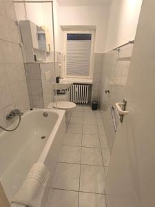 a white bathroom with a tub and a toilet at BR Apartment in Kiel