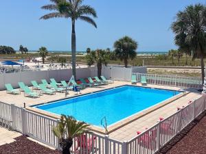 a swimming pool with chairs and a palm tree at Arvilla Resort in St. Pete Beach